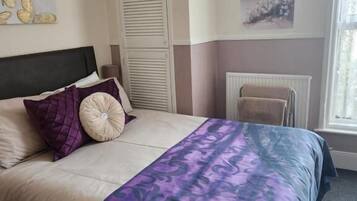 A bedroom with a bed, a radiator, and artwork on the walls.