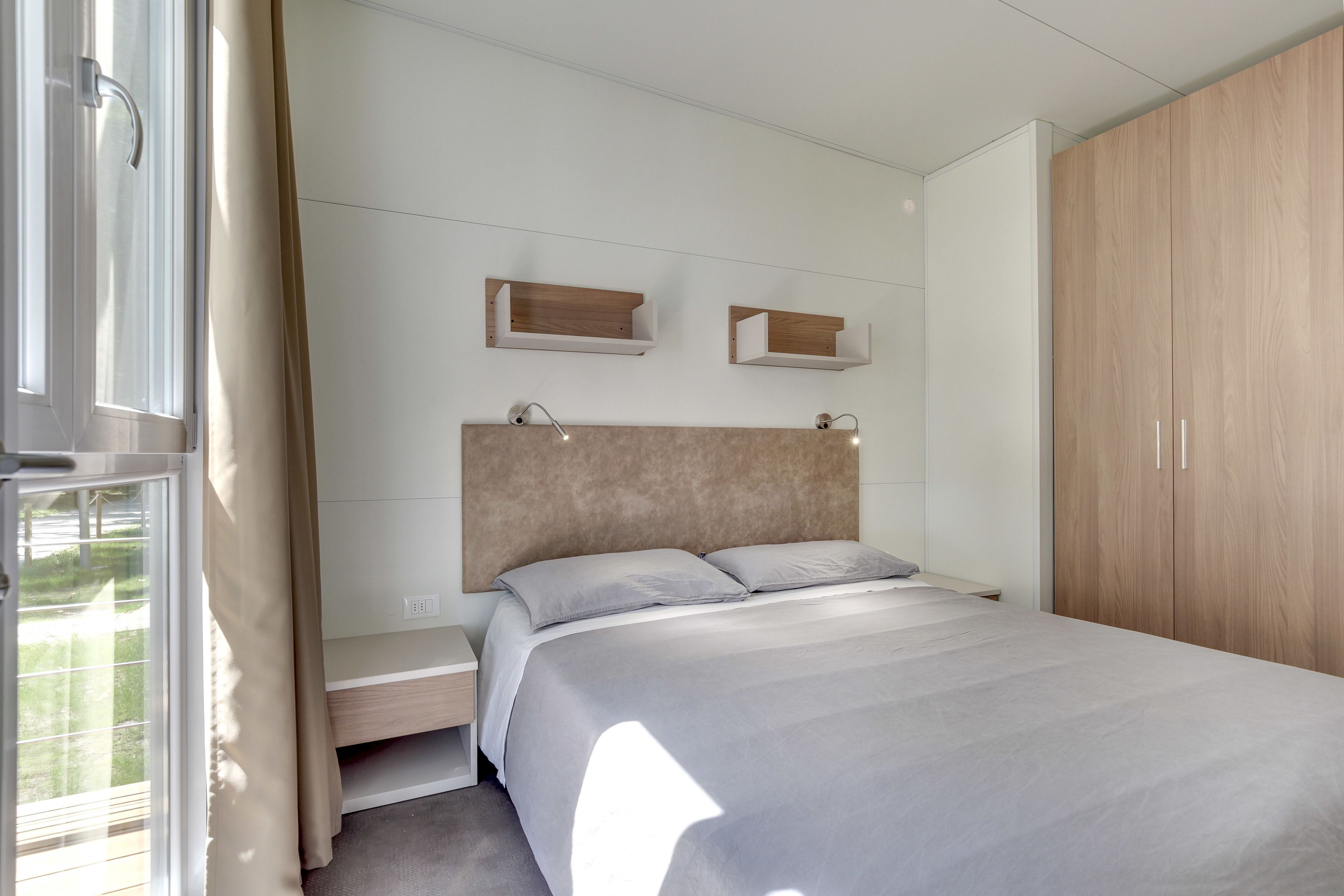 A modern bedroom with a bed, wooden wardrobe, and built-in shelves.