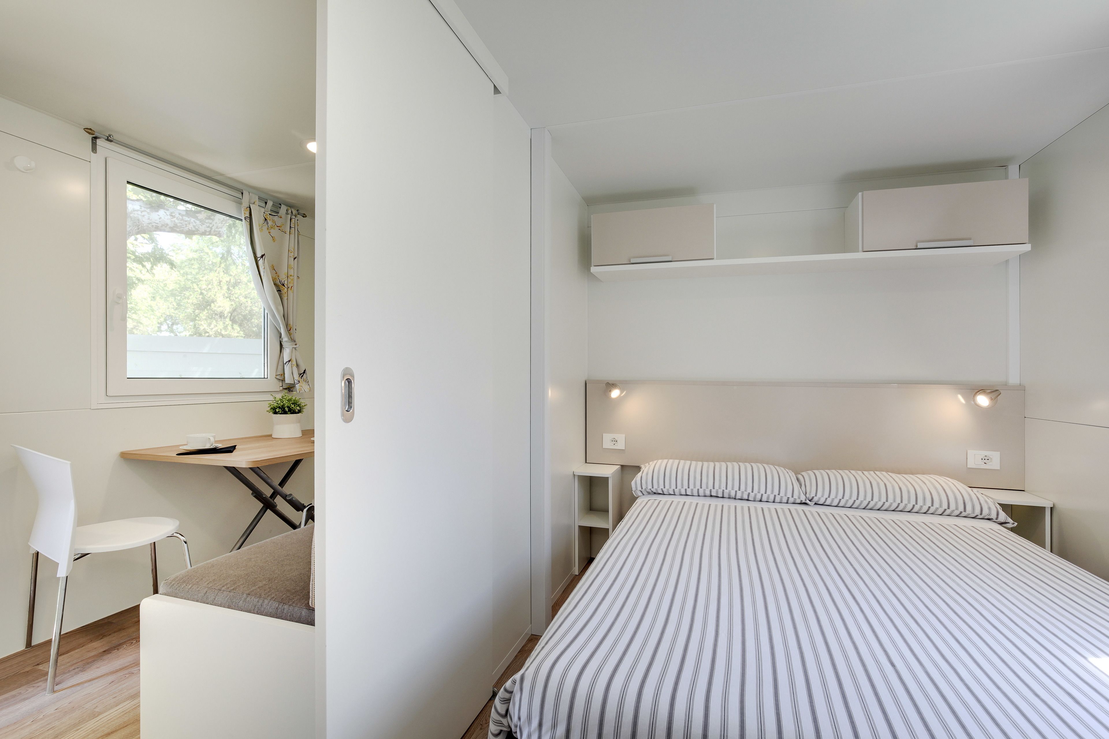 Un dormitorio moderno y funcional con cama, mesitas de noche, escritorio y silla.