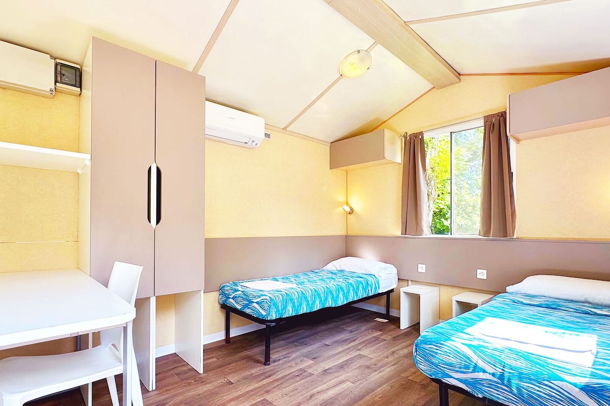 A compact room with a bed, a desk, and a wardrobe.