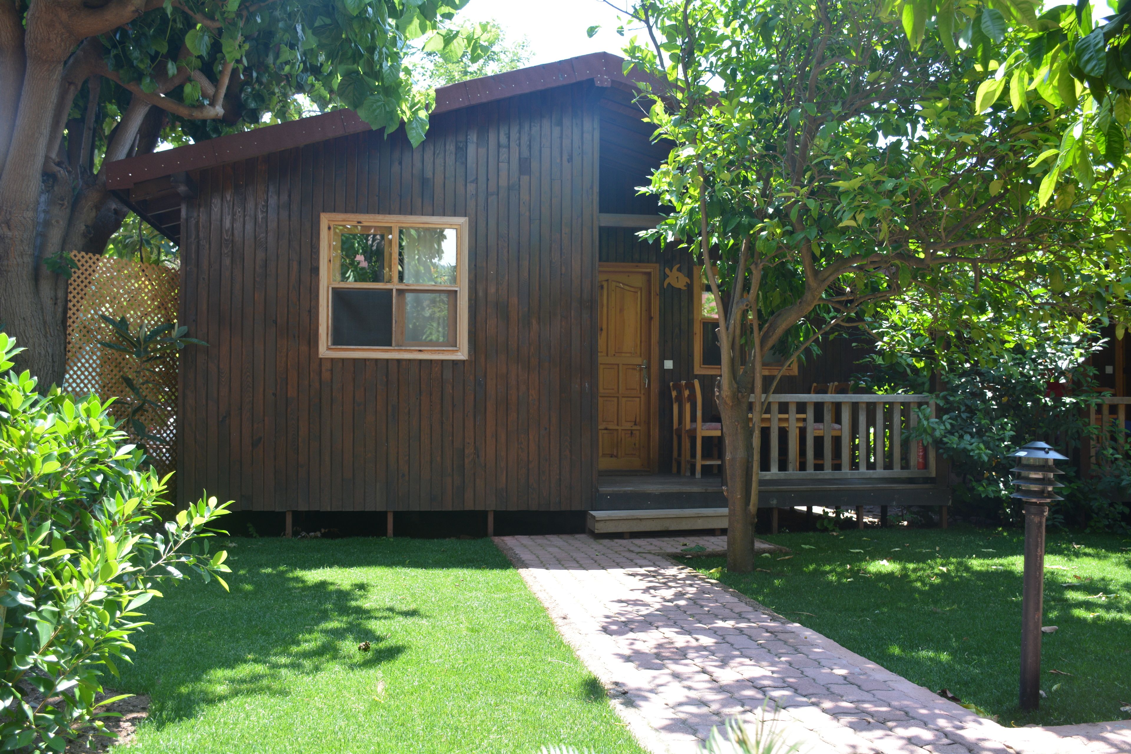 A small wooden cabin with a front door, a window, and a porch.