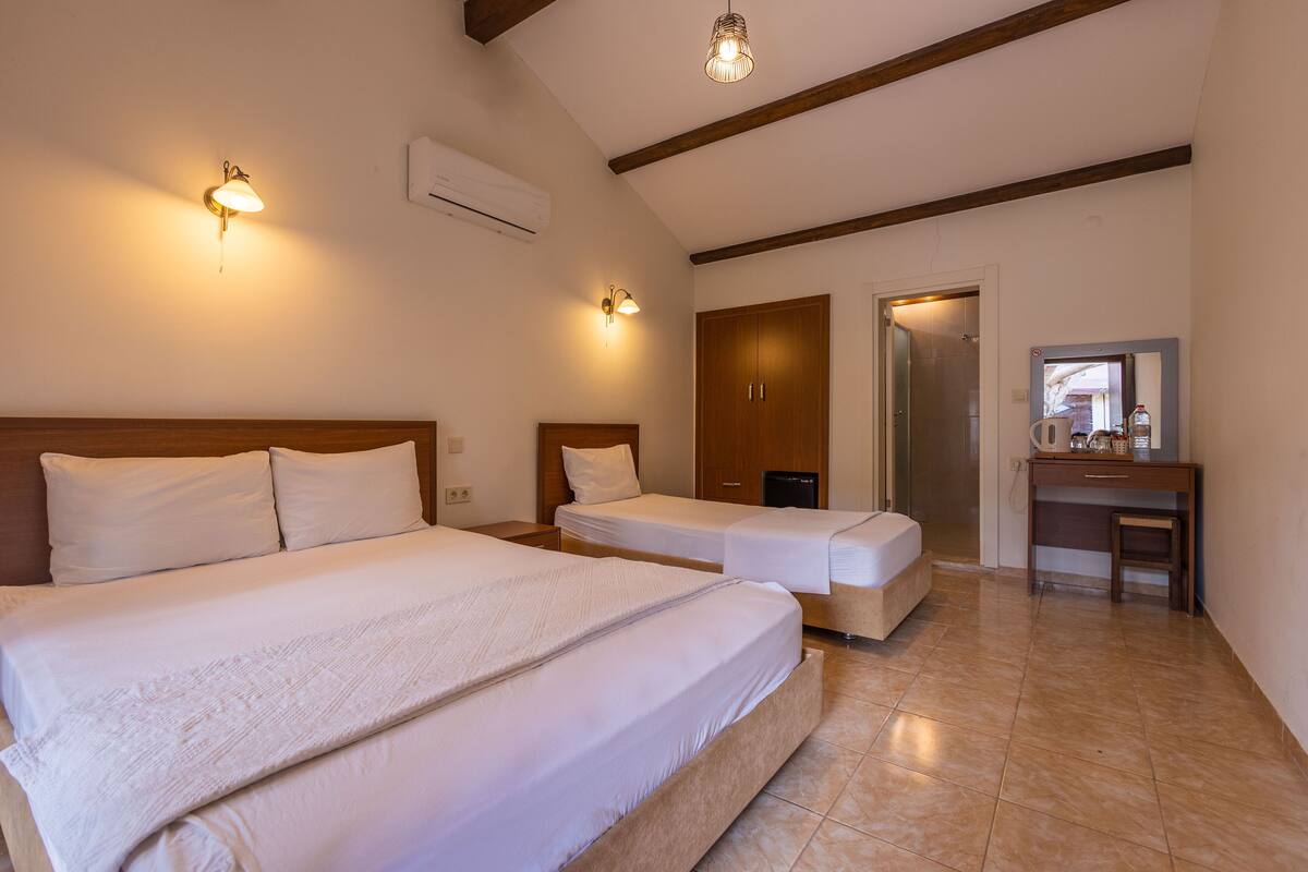 A hotel room with two beds, a desk, a mirror, and a wardrobe.