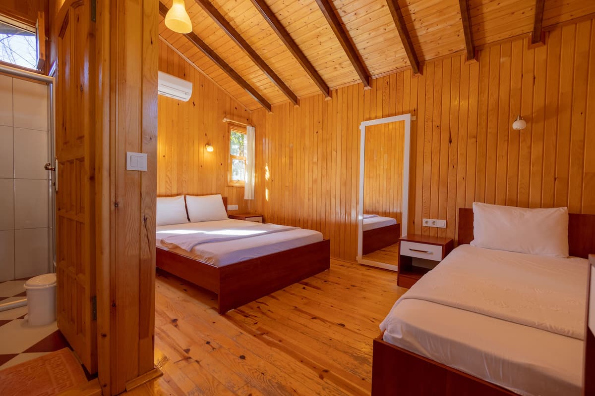 A wooden-paneled room with two beds, a mirror, and a window.