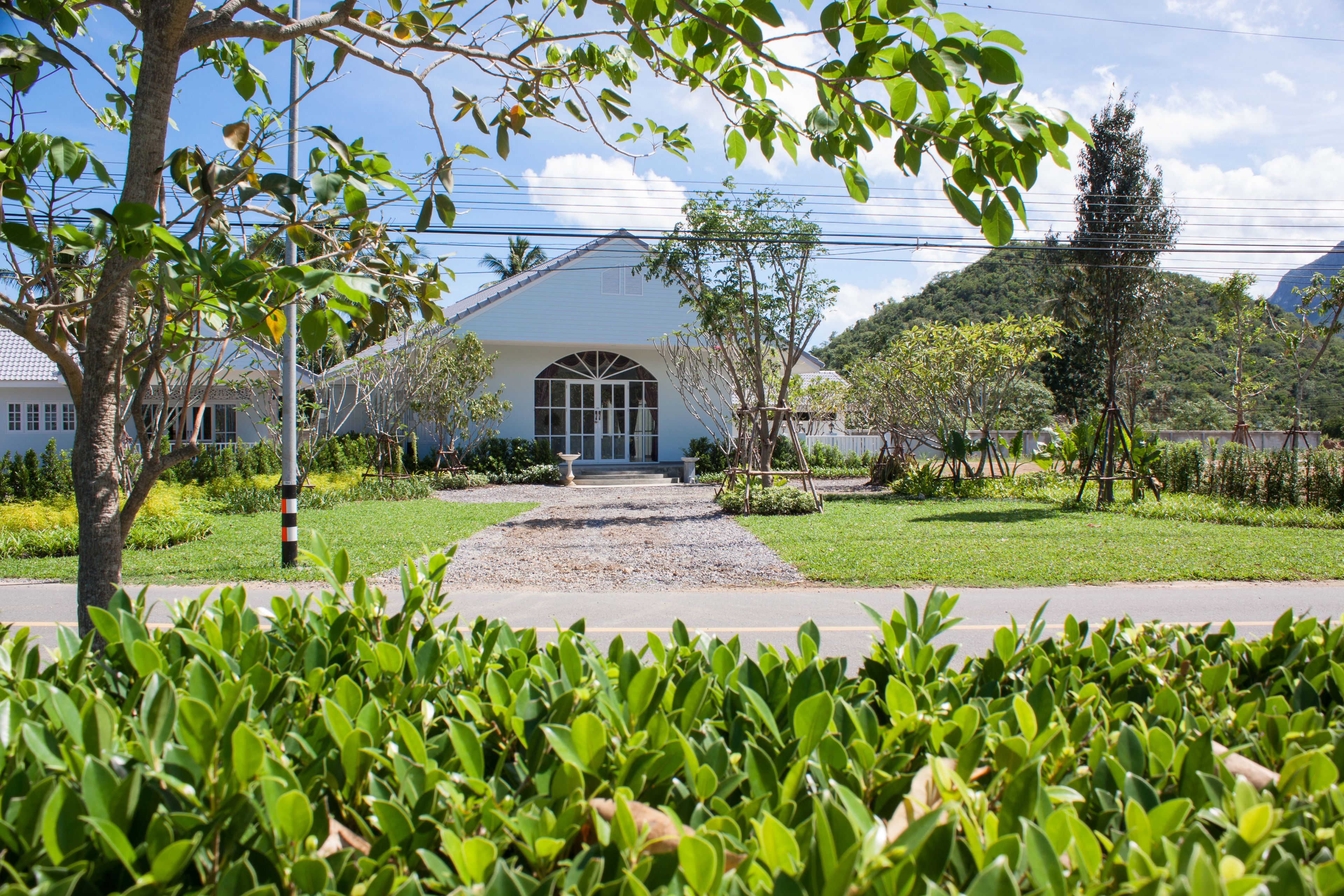 A building with a large arched entrance, surrounded by well-maintained greenery and a clear sky.