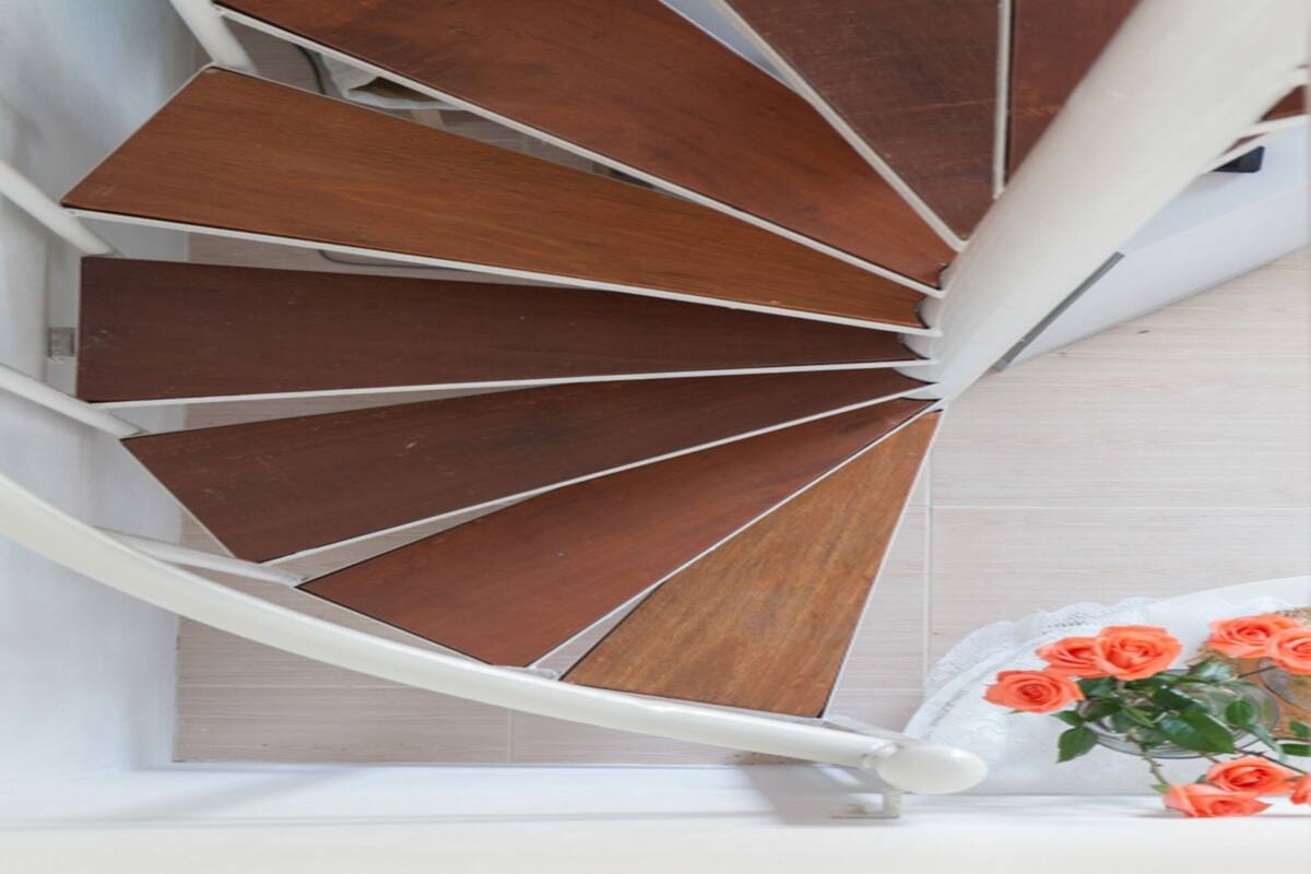 Eine Wendeltreppe mit Holzbodenstufen und weißen Geländern.