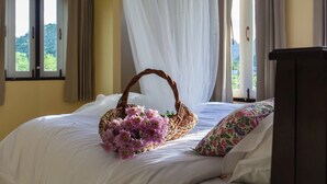 A bed with a white bedspread, a wicker basket with flowers, and a floral pillow. - Sweet Honey Resort, Pranburi - Hua Hin (Sam Roi Yot)