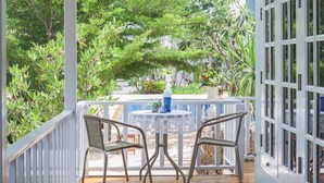 A covered outdoor seating area with a table and chairs, surrounded by lush greenery and a white railing. - Sweet Honey Resort, Pranburi - Hua Hin (Sam Roi Yot)