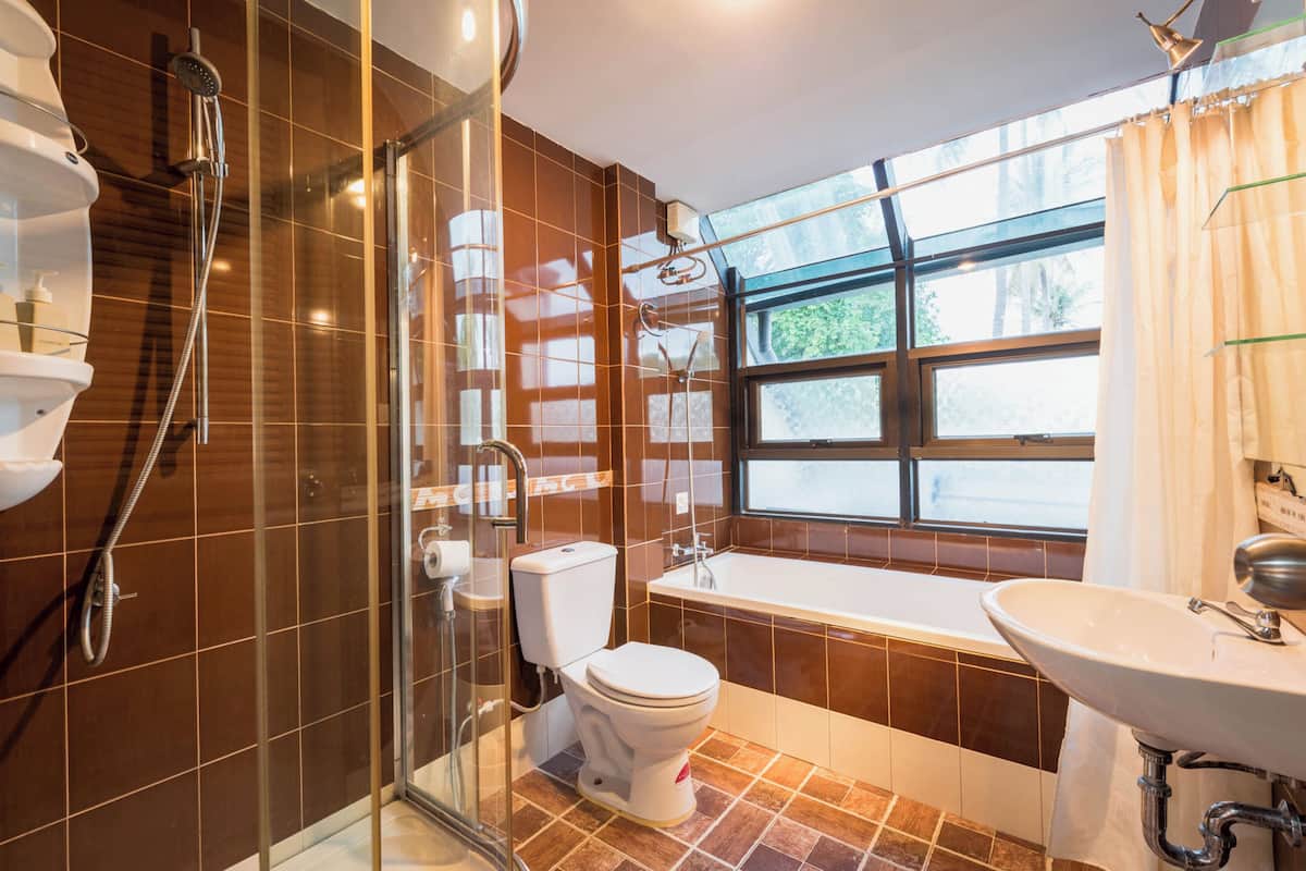 Ein modernes Badezimmer mit einer in Glas abgeschlossenen Dusche, einer weißen Toilette, einer Badewanne und einem Waschbecken.