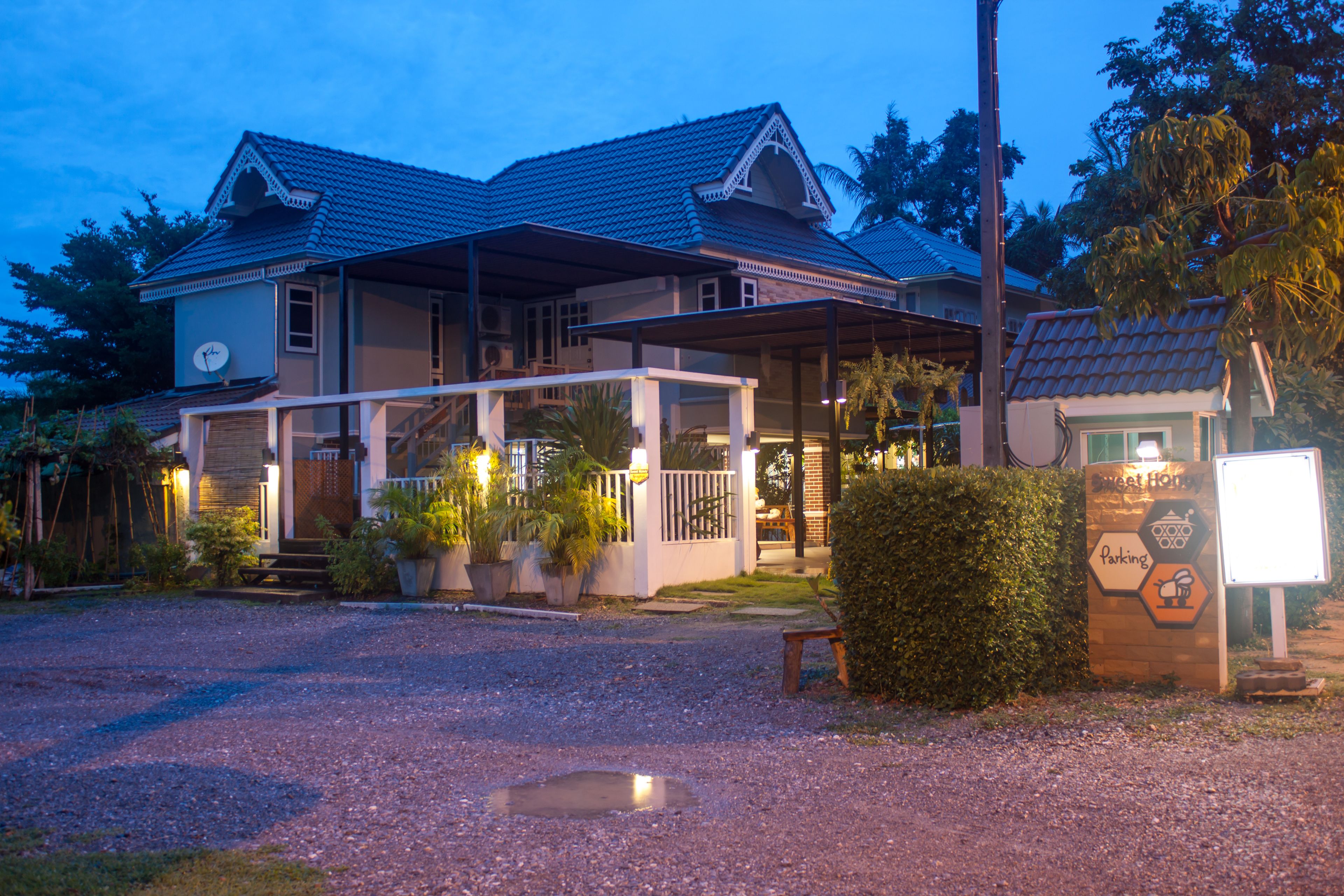 A two-story building with a covered porch and a gravel driveway.