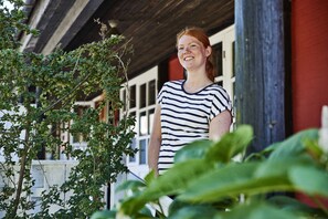 A person standing in front of a building with a wooden structure and a red wall. - Rosengaarden Hostel (Akirkeby)