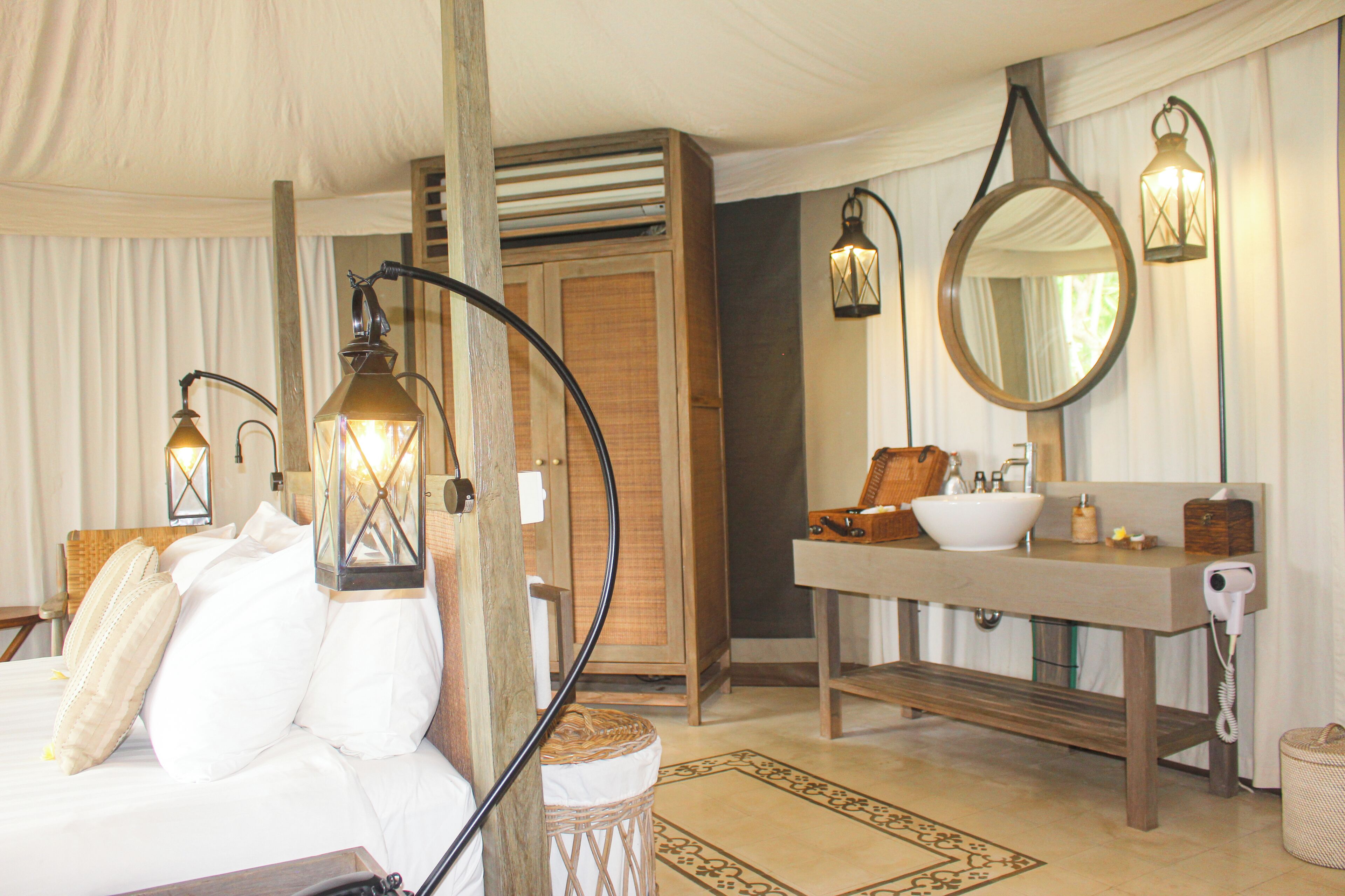 Une chambre à coucher avec un lit, une lampe de chevet, une tête de lit en bois et un grand miroir au-dessus du lavabo.