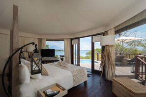 Une chambre d’hôtel avec un lit, un bureau, une télévision et une vue sur la mer.