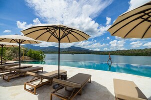 Una piscina al aire libre, sombrillas, sillones reclinables de piscina