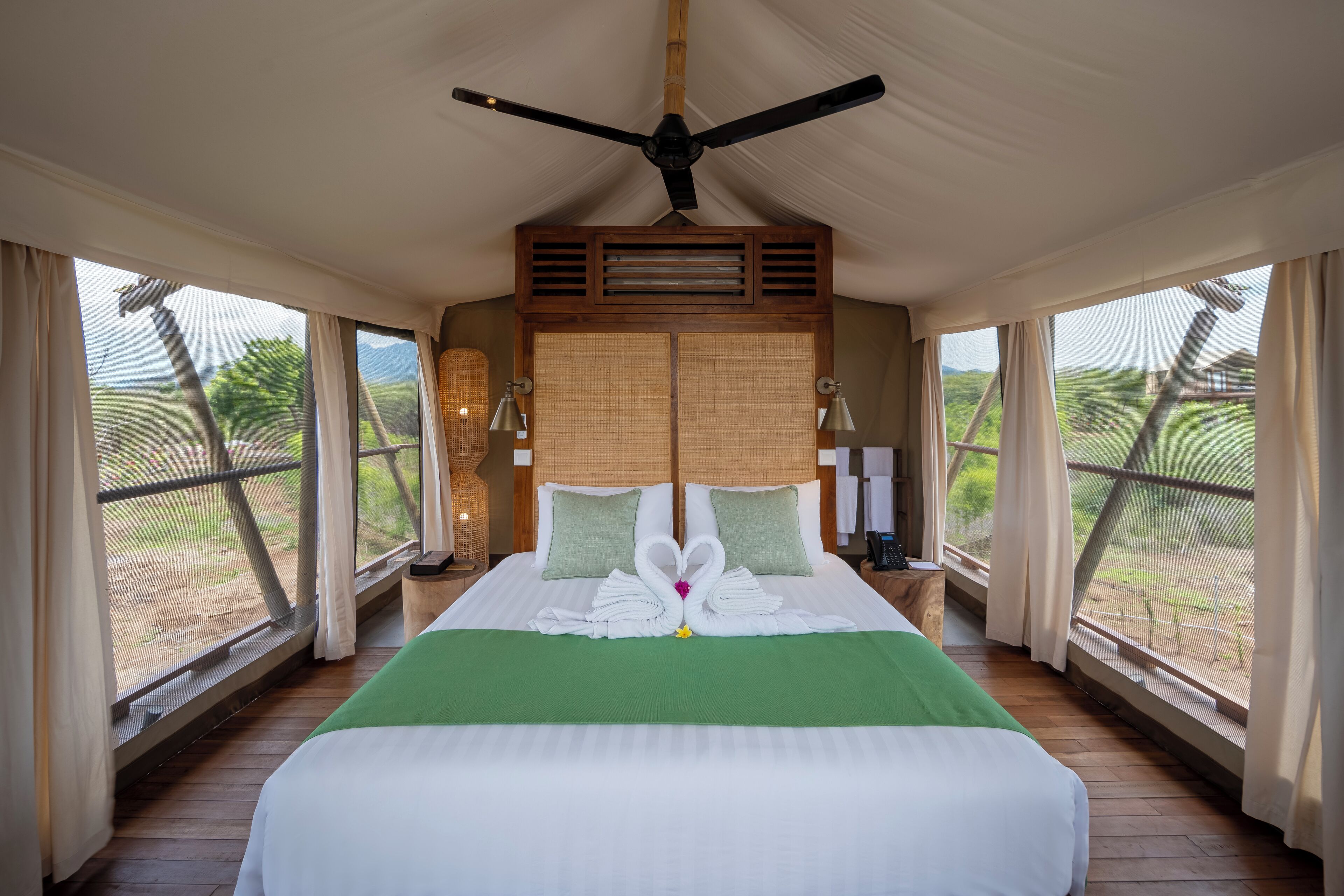 Una habitación amplia con una cama grande, ventilador de techo y vista al exterior.