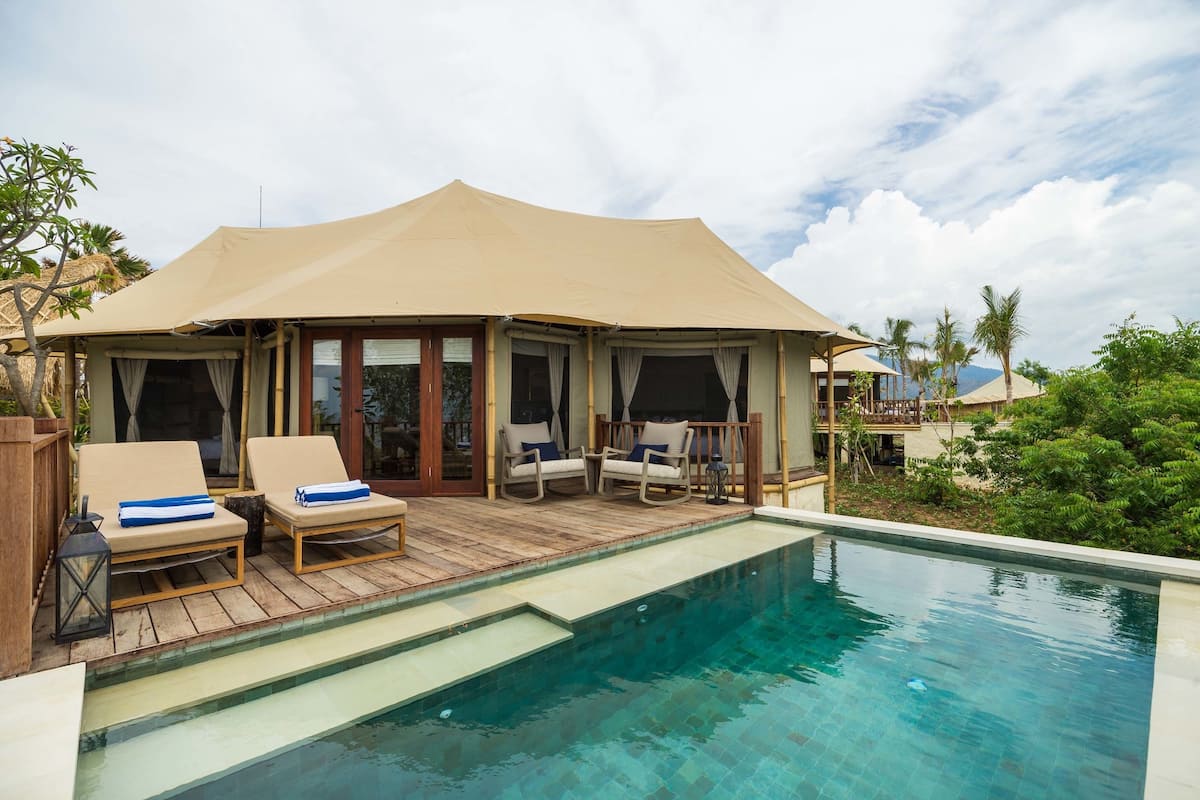 A poolside area with lounge chairs and a covered seating area.