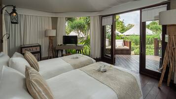A hotel room with two beds, a desk with a television, and a sliding glass door leading to an outdoor area.
