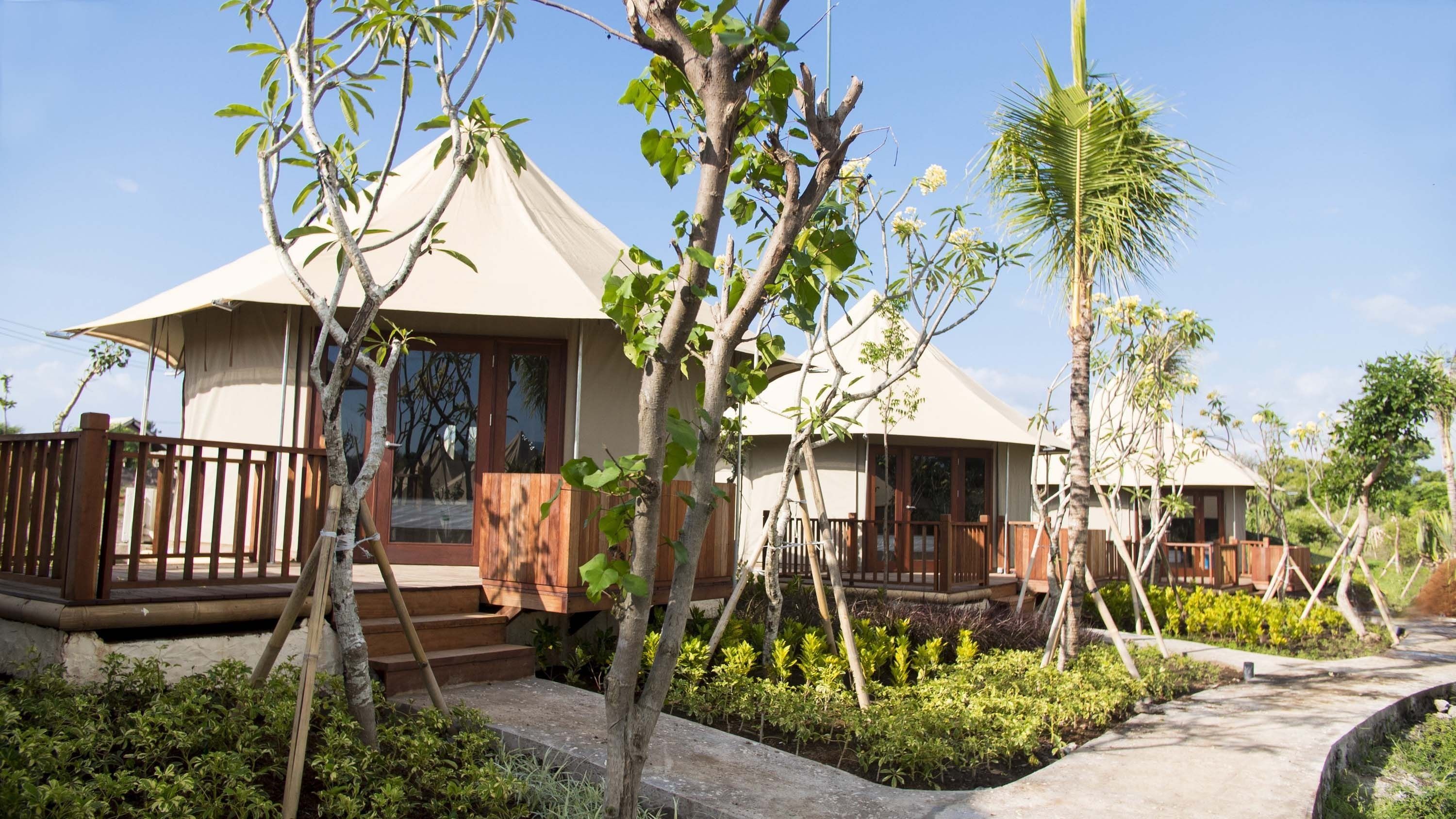 A bungalow-style accommodation with a covered porch, wooden deck, and lush garden.