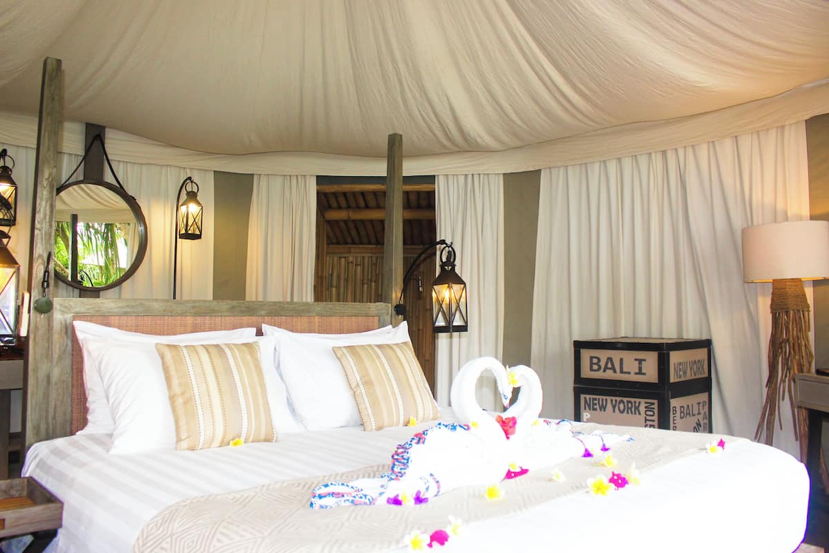 A hotel room with a large bed, white curtains, and a sign that reads "BALI NEW YORK".