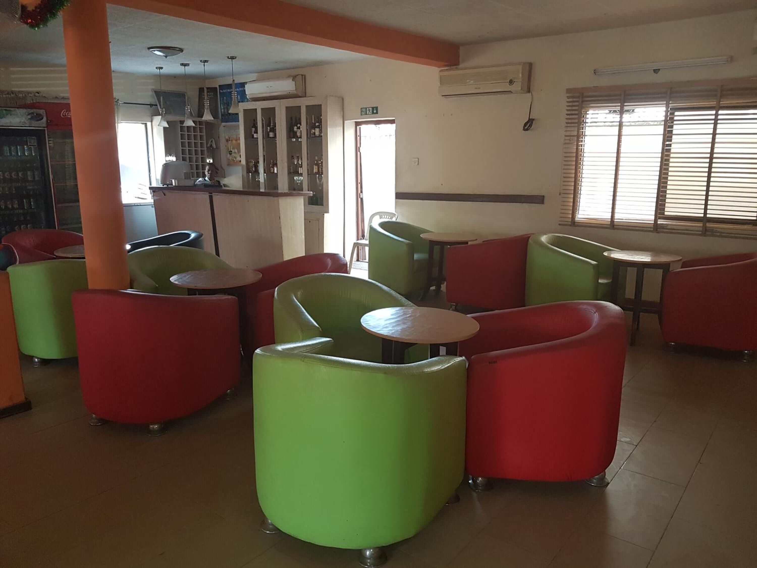 A restaurant with green and red booths, a bar area, and a window with blinds.