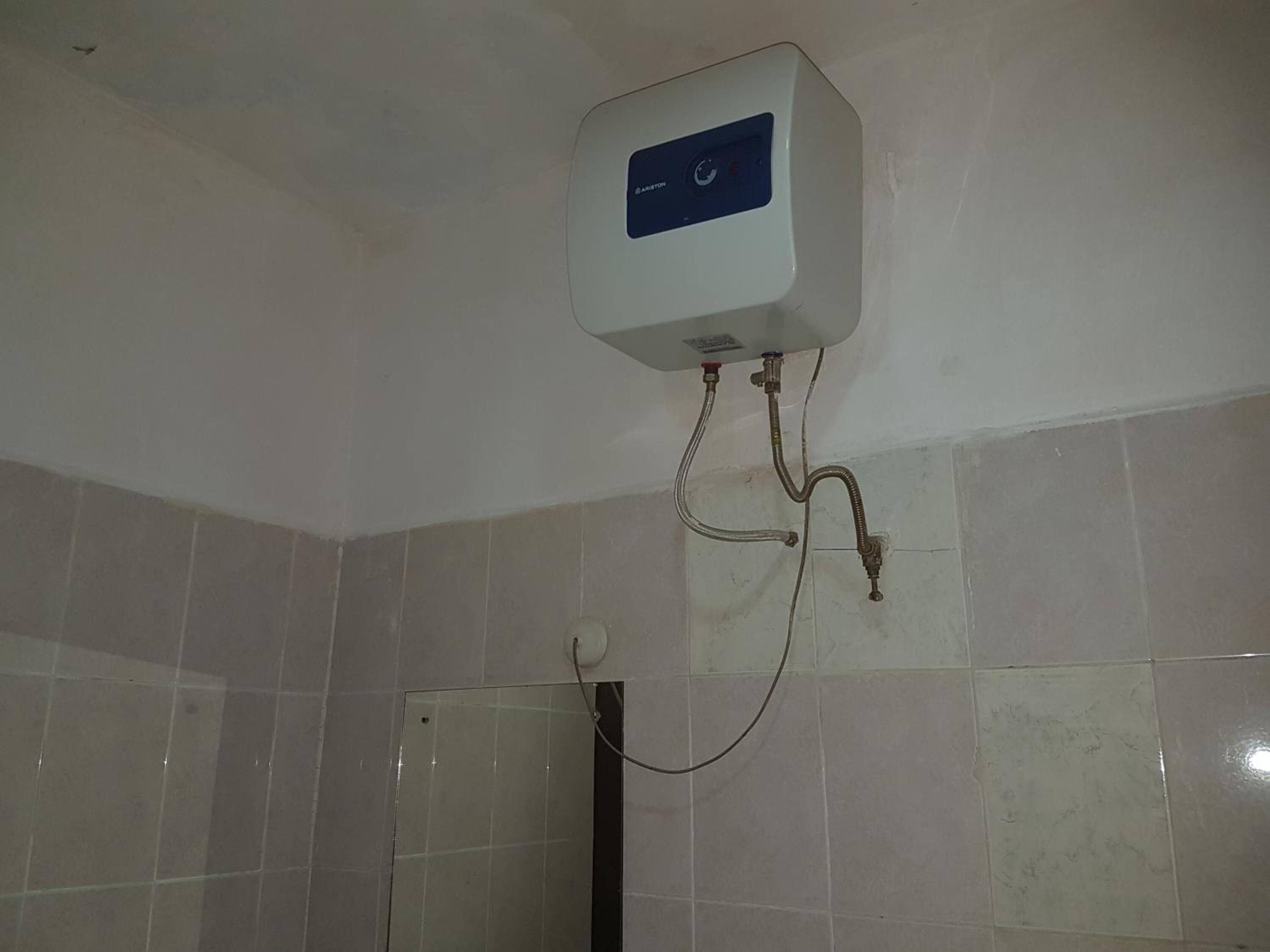 Calentador de agua instalado en una pared con azulejos y un panel de control.