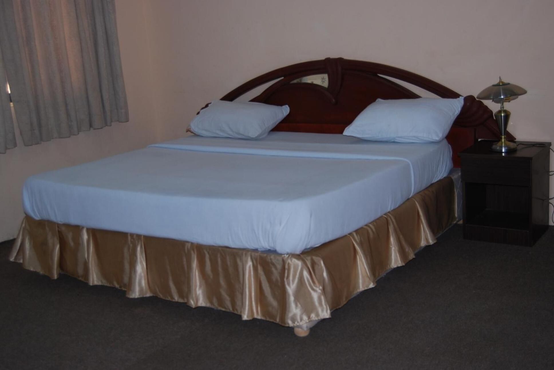 A standard hotel room with a single bed, a nightstand, and a lamp.