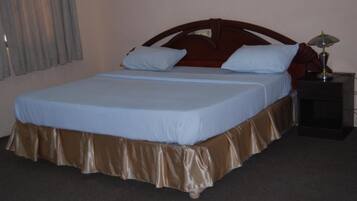 Una habitación de hotel estándar con una cama individual, una mesita de noche y una lámpara.
