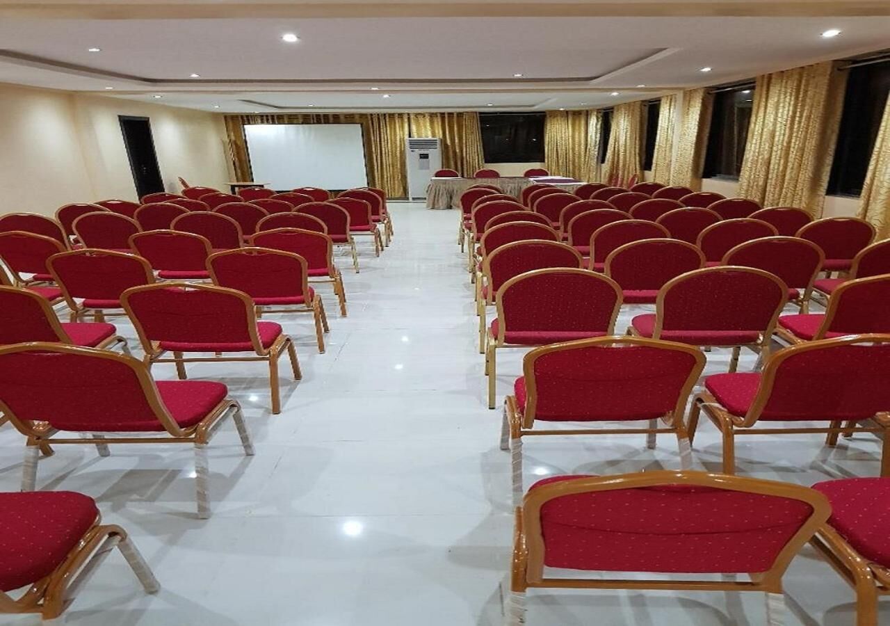 A conference room with rows of red chairs and a whiteboard at the front.