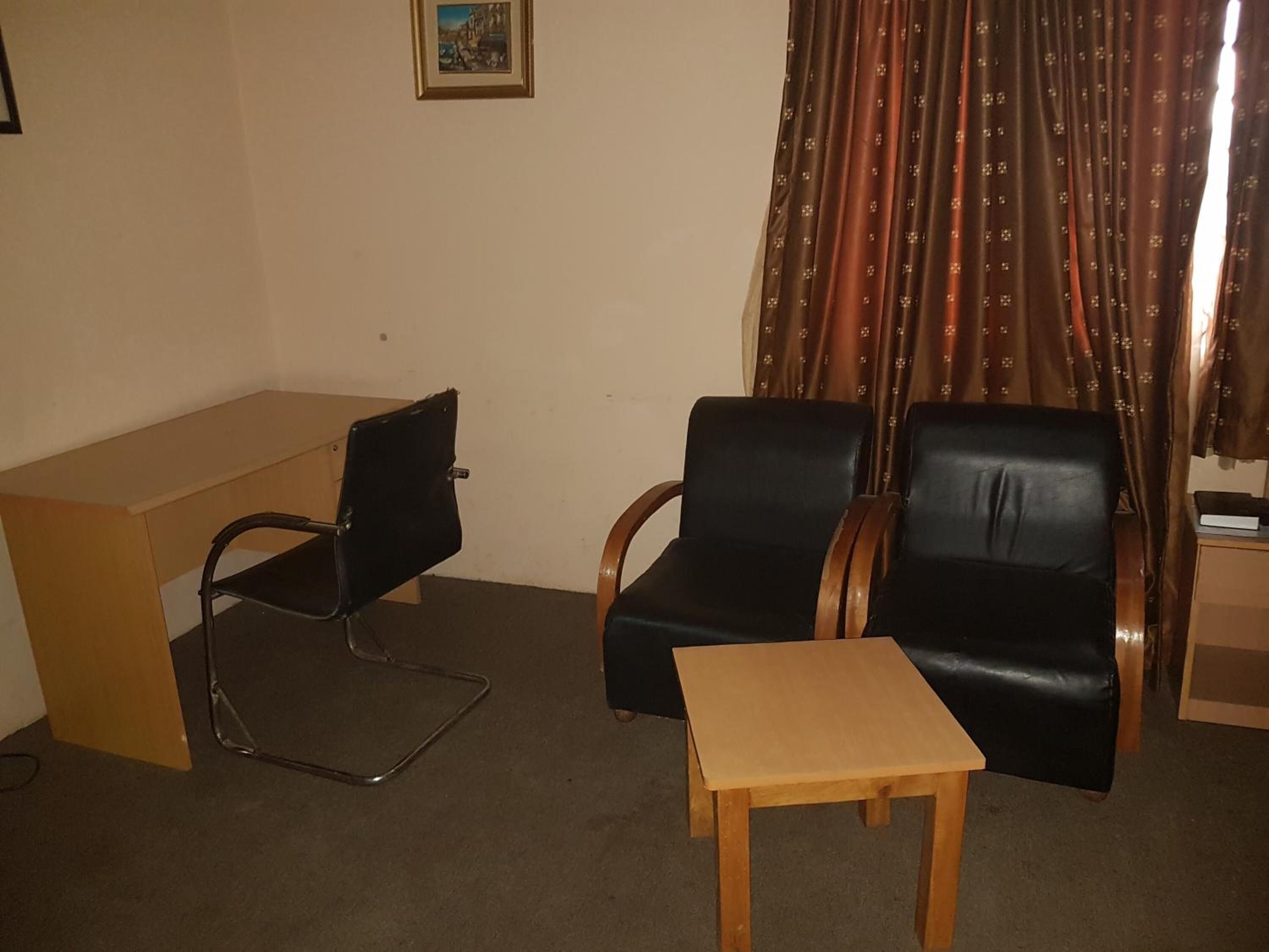 A room with a desk, two chairs, and a small table.