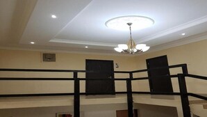 Une pièce à plusieurs niveaux, dotée d’une rambarde noire, d’un lustre et d’un ventilateur de plafond.