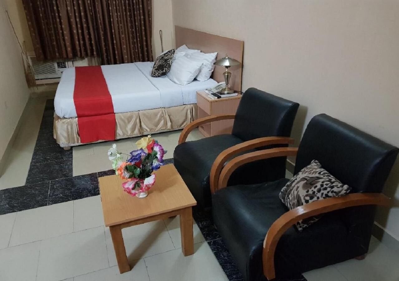 Une chambre d’hôtel comprenant un lit, une table de chevet, un bureau et deux chaises.