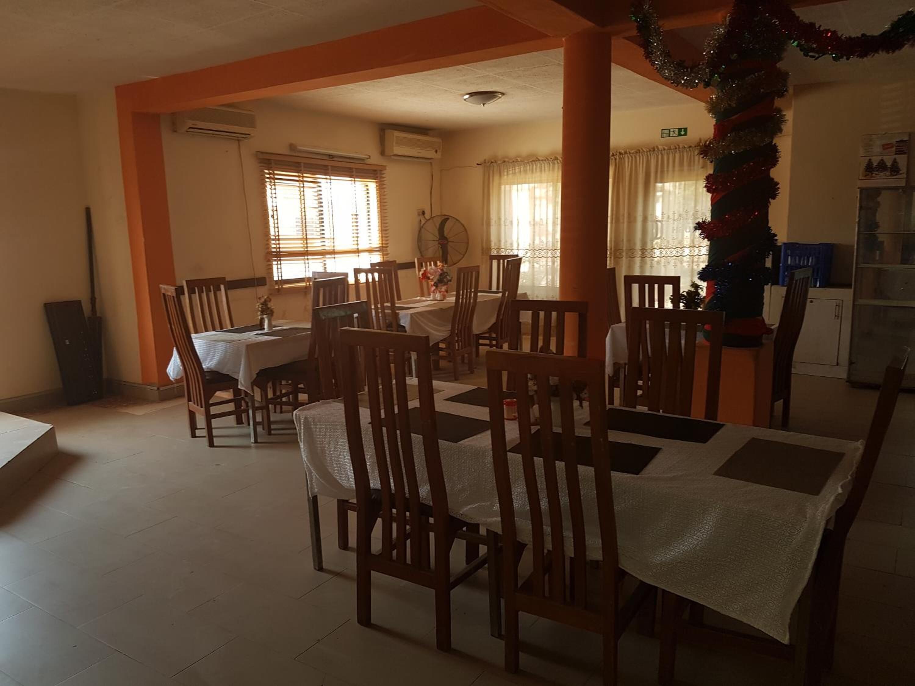 A dining area with wooden chairs and tables, air conditioning units, and a Christmas tree decoration.