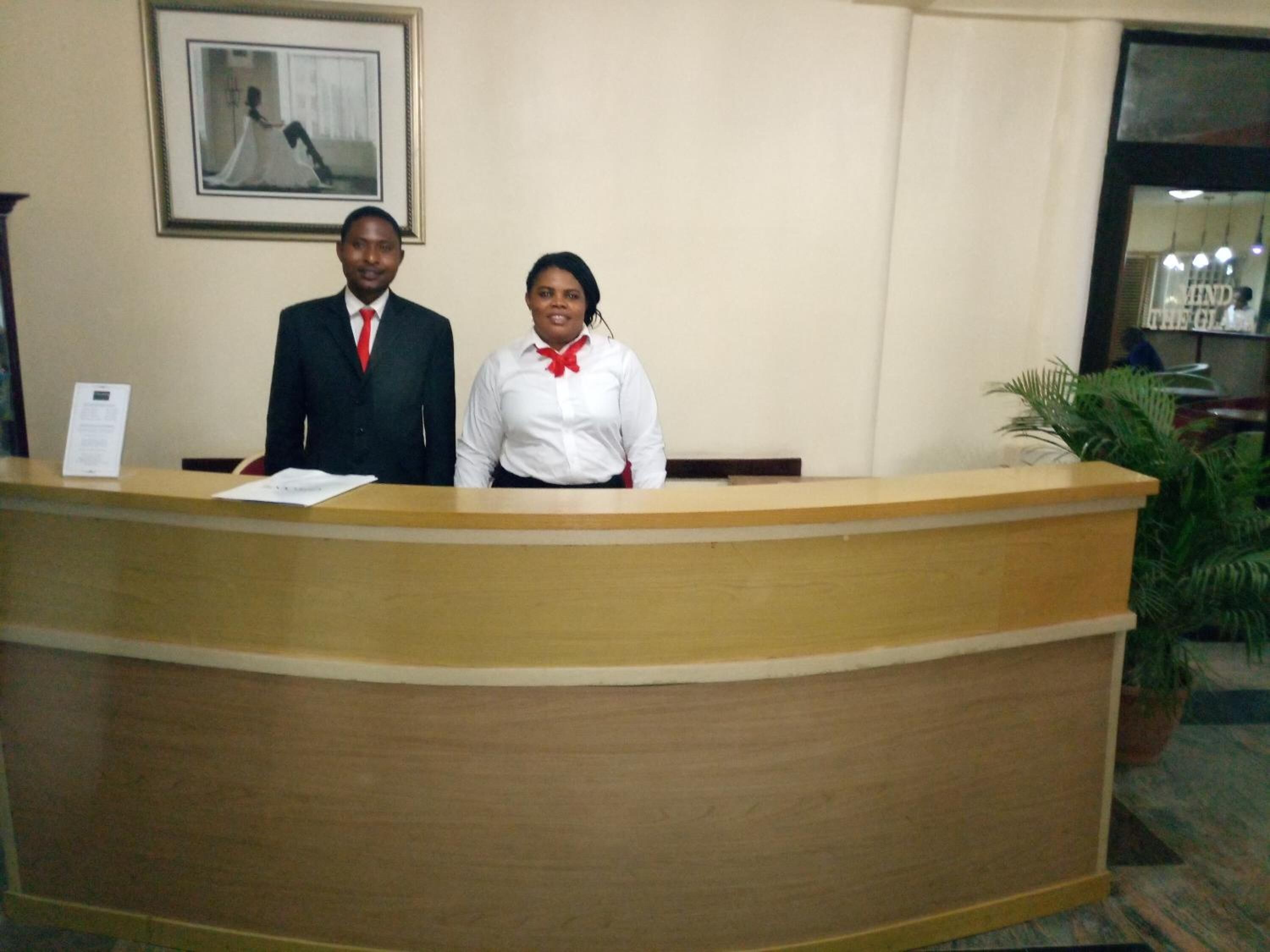 A reception desk with two individuals standing behind it.
