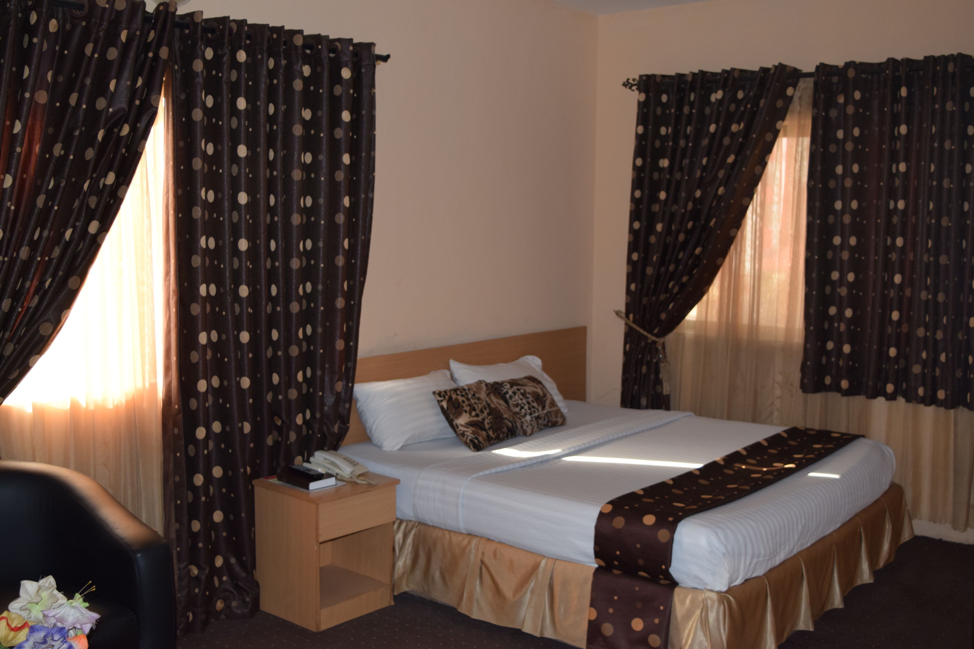 A hotel room with a bed, nightstand, and a chair.