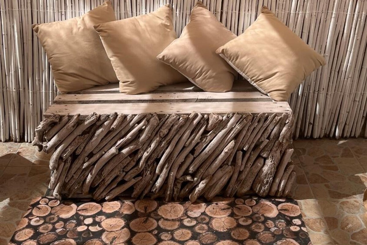 A bed with a woven headboard, a circular wooden object above it, and a patterned rug on the floor.