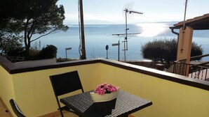 Un balcón con una mesa y sillas, un florero y vista al mar.