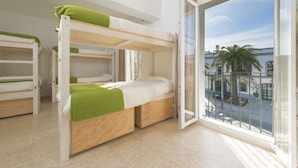 A room with bunk beds, a sliding glass door to the outside, and a view of the street. - Tarifa Kite Hostel (Tarifa)