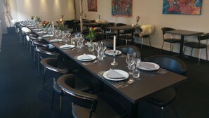 Una larga mesa de comedor dispuesta con sillas, velas y obras de arte en las paredes.