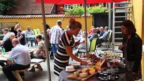 Un área de comedor al aire libre con mesas, sillas y una mesa de bufé con diversos alimentos y bebidas.