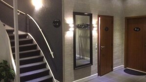 Un interior moderno con una escalera, un espejo grande y una puerta de madera.