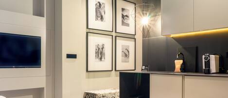 Una sala de estar moderna con televisor de pantalla plana, obras de arte enmarcadas en la pared, una mesa de centro y una zona de estar.