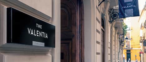 A sign for "The Valentina" hotel with a classic architectural facade.