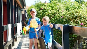 Two children on a wooden deck with a railing, holding badminton rackets and shuttlecocks.