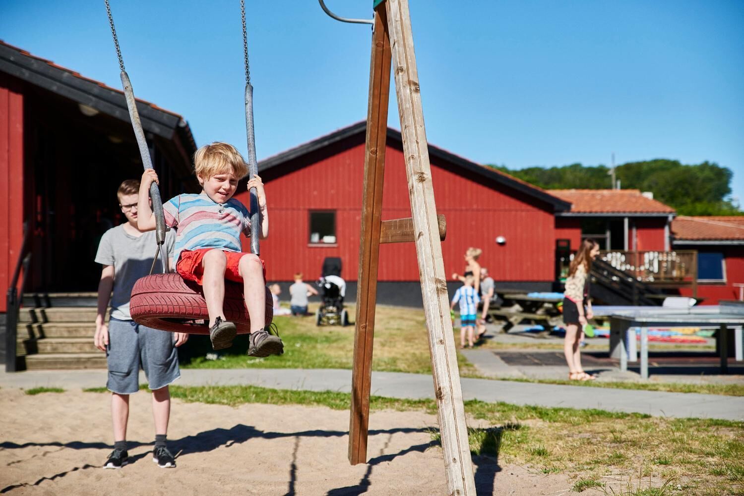 A child on a swing with a red barn in the background.