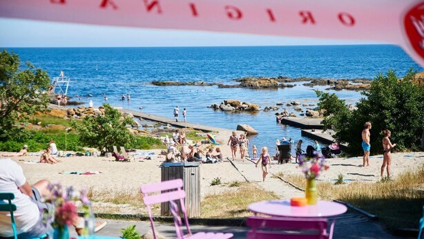 A beach with people, a lifeguard tower, and a rocky shoreline.
