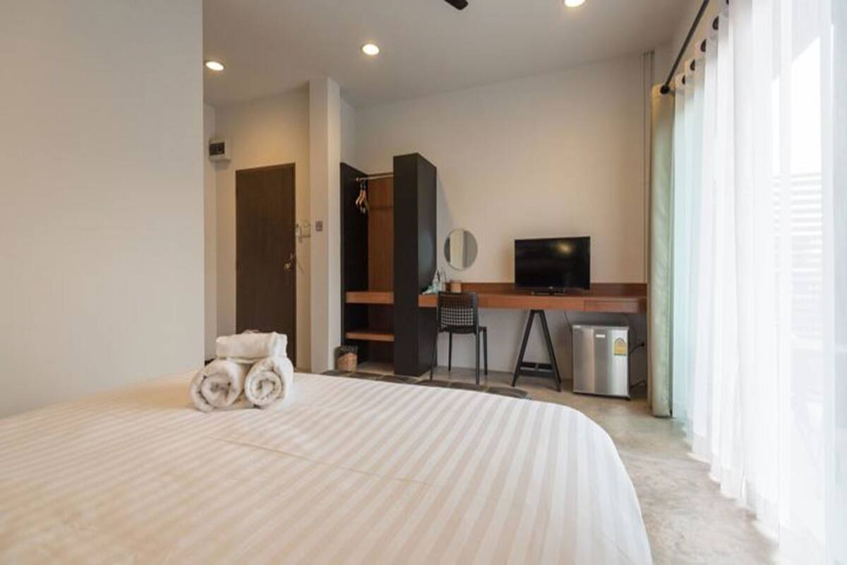 A hotel room with a bed, a desk, a television, and a small refrigerator.