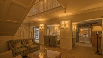 A spacious living area with a high ceiling, a staircase, a dining area, and a kitchen visible through an open door.