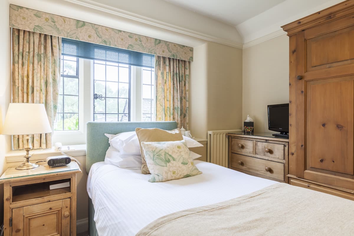 Une chambre à coucher comprenant un lit, une table de chevet, une commode et un téléviseur.