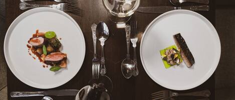 A dining table set with plates of food, cutlery, and a glass of water.