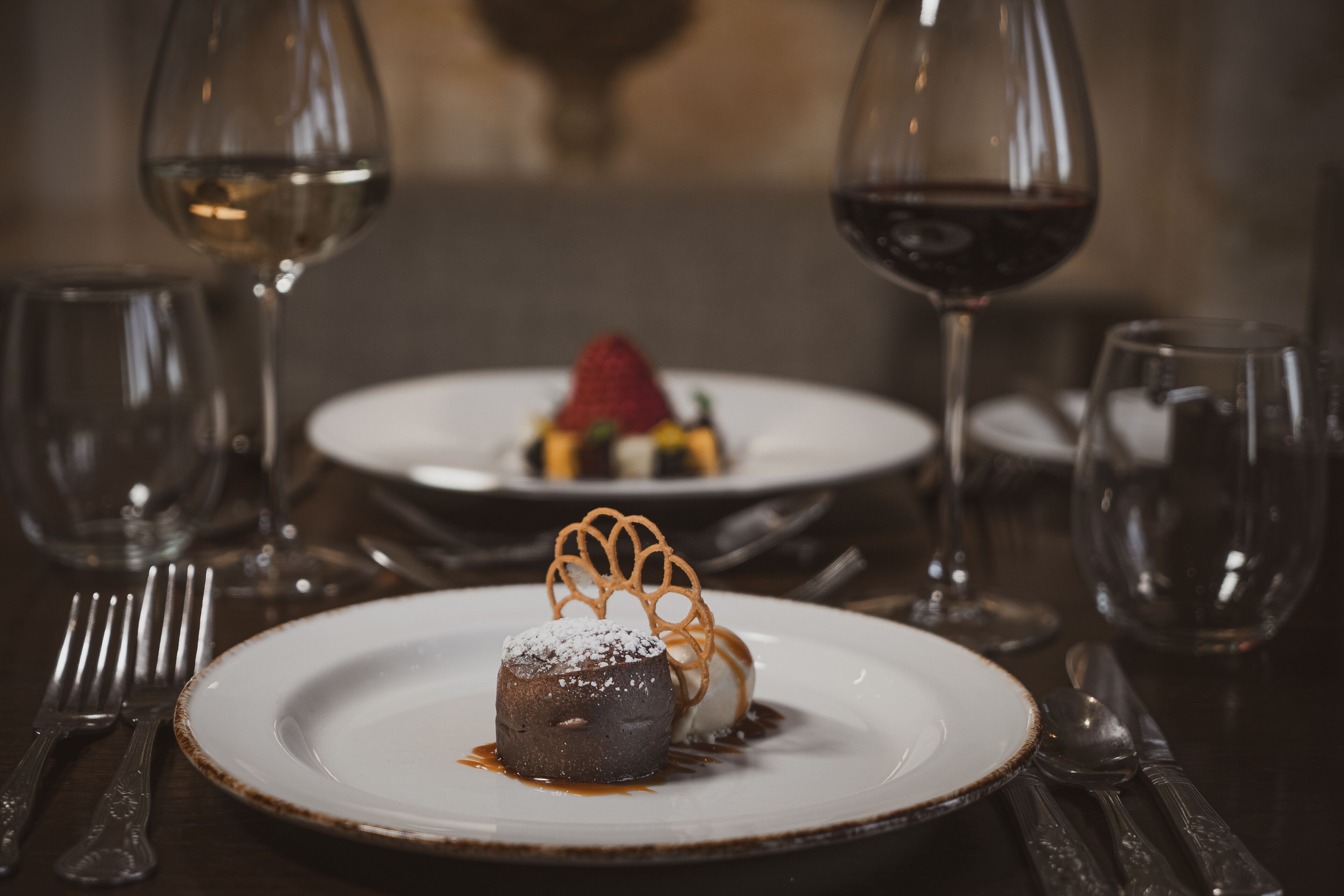 A dessert plate with a chocolate lava cake, a scoop of ice cream, and a strawberry on a white plate.