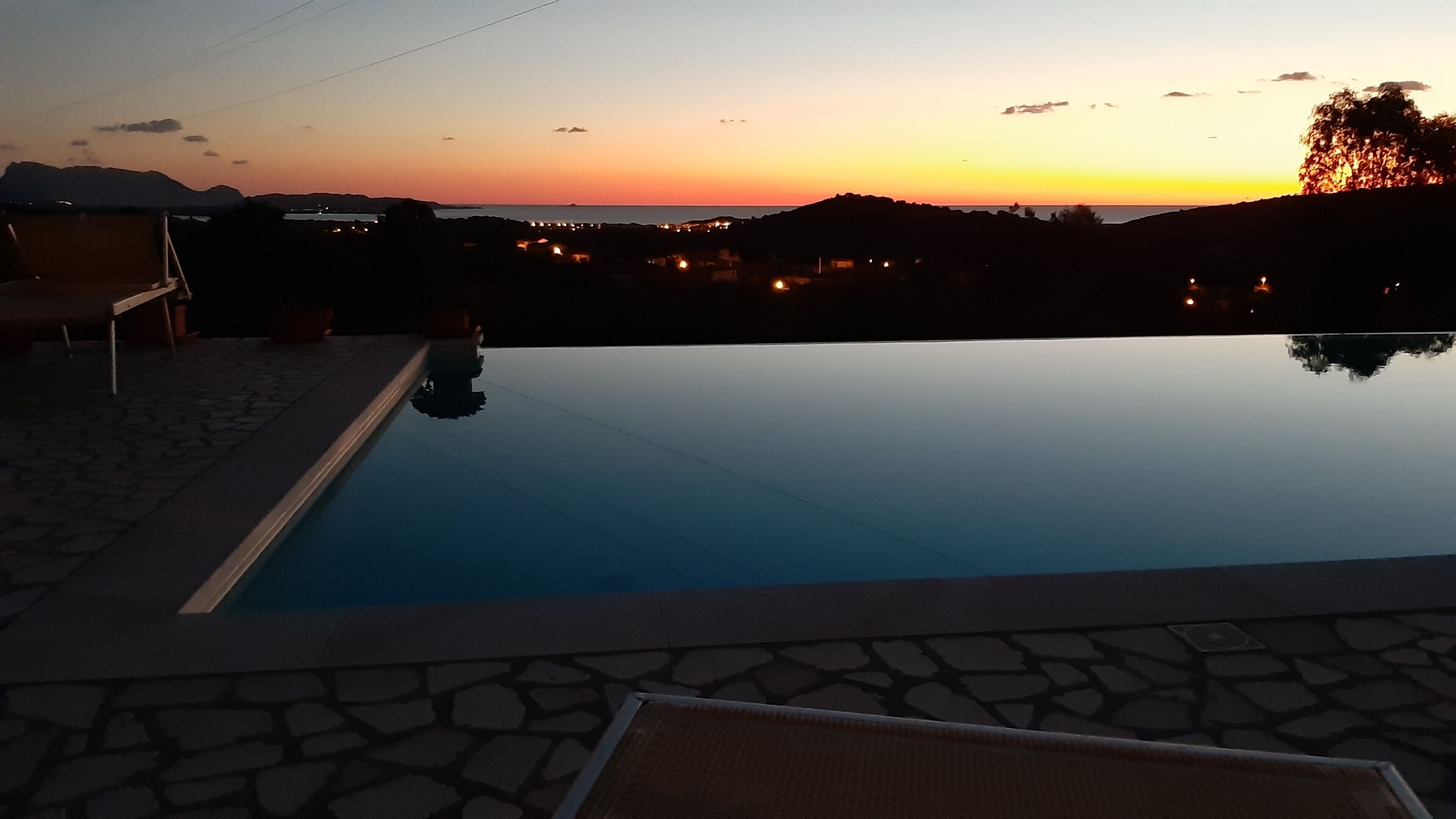 En swimmingpool med fri utsikt över solnedgången i bakgrunden.